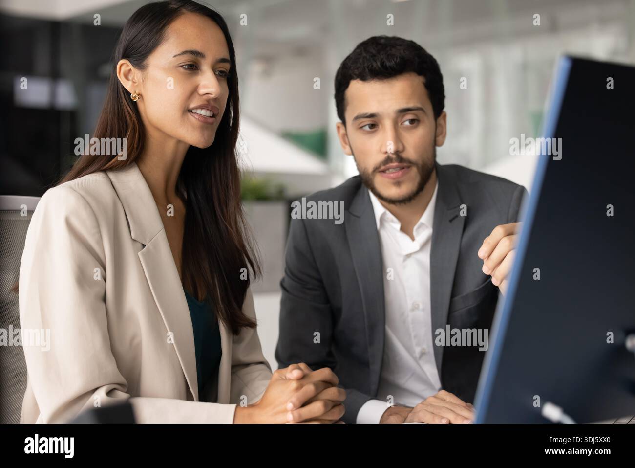 Two colleagues reviewing platform, discussing joint project details on computer Stock Photo