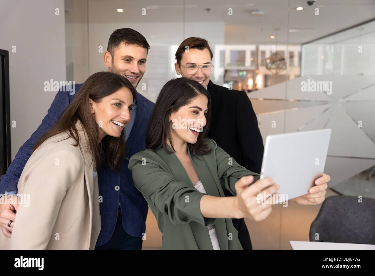 Four colleagues gather to take group selfie on digital tablet Stock Photo