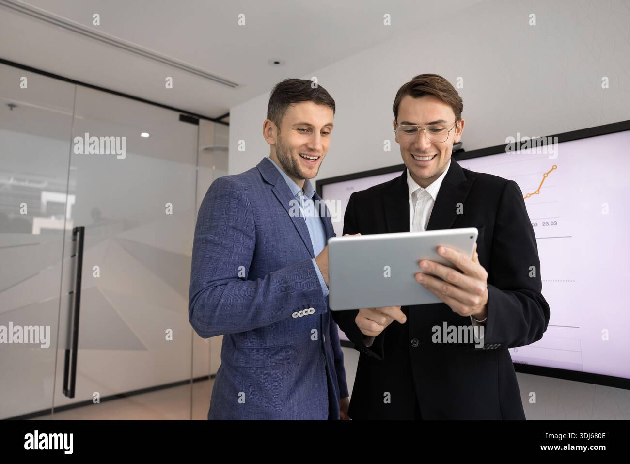 Two businessmen discussing successful project data using tablet Stock Photo