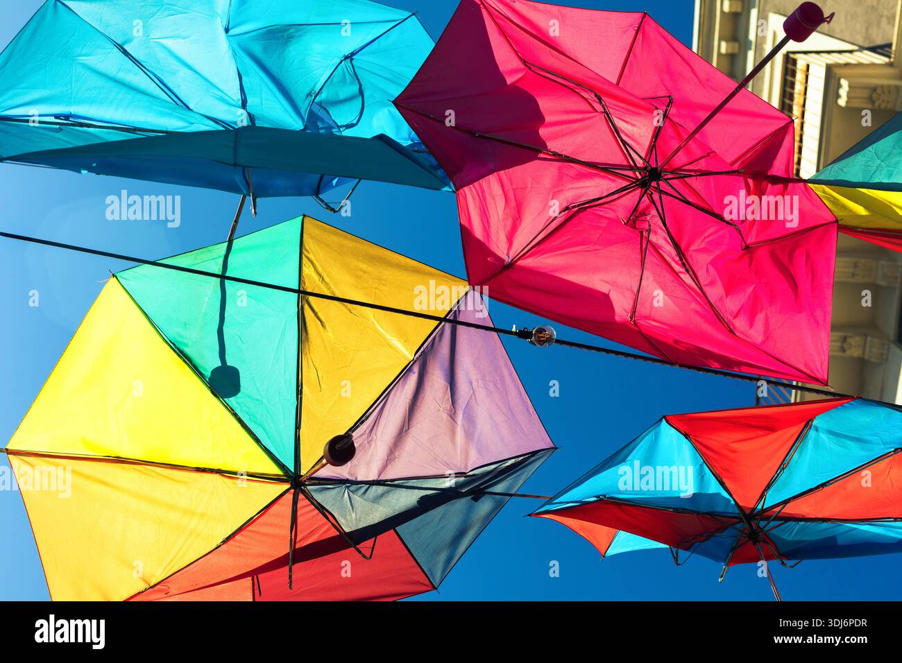 Visual Interest Images Colorful umbrellas are suspended overhead against a bright blue sky ...
