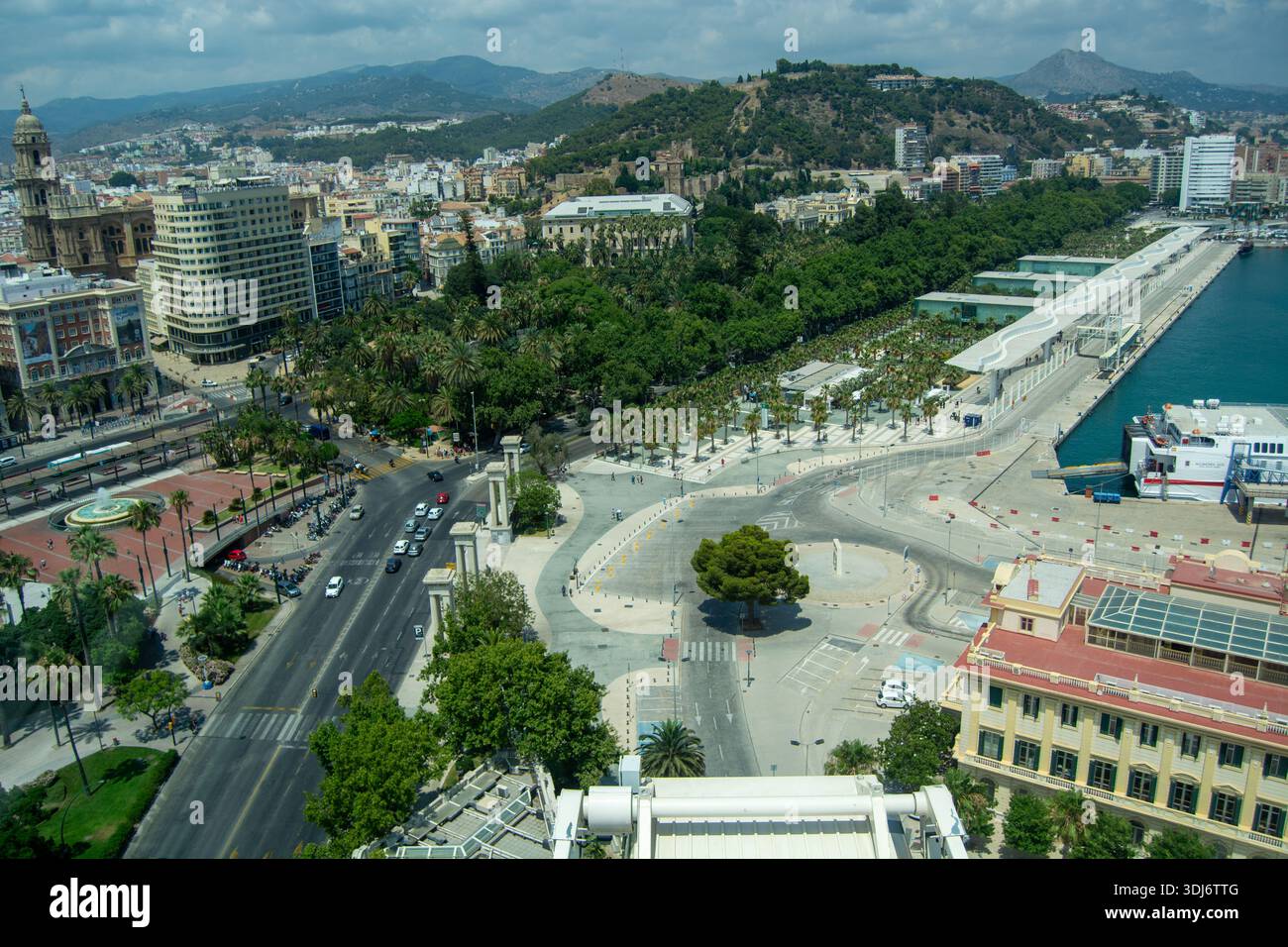 Aerial view of a coastal city with a promenade, trees, and mountains ...