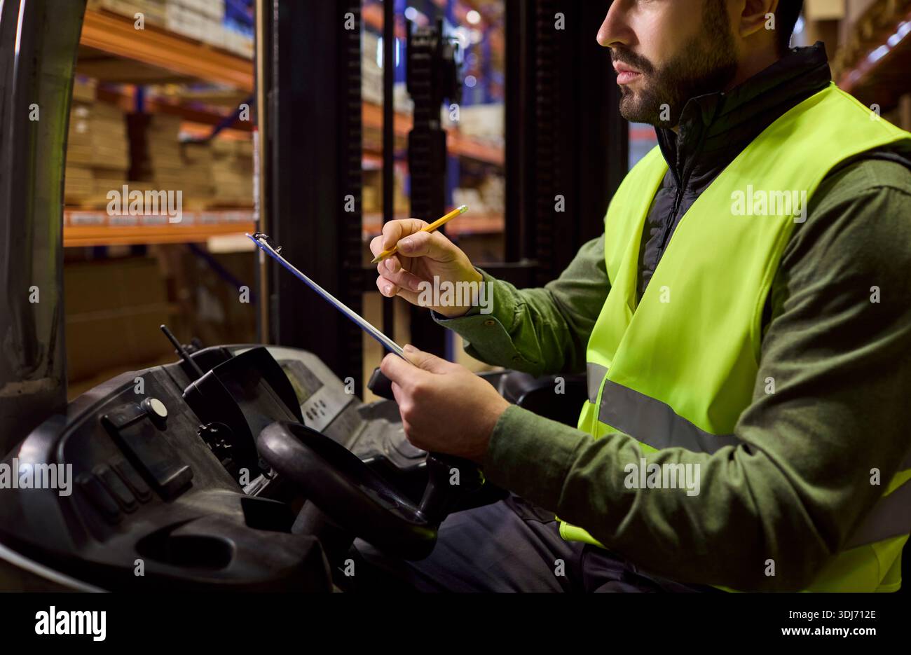 Forklift operator checking clipboard for inventory in warehouse loading goods Stock Photo