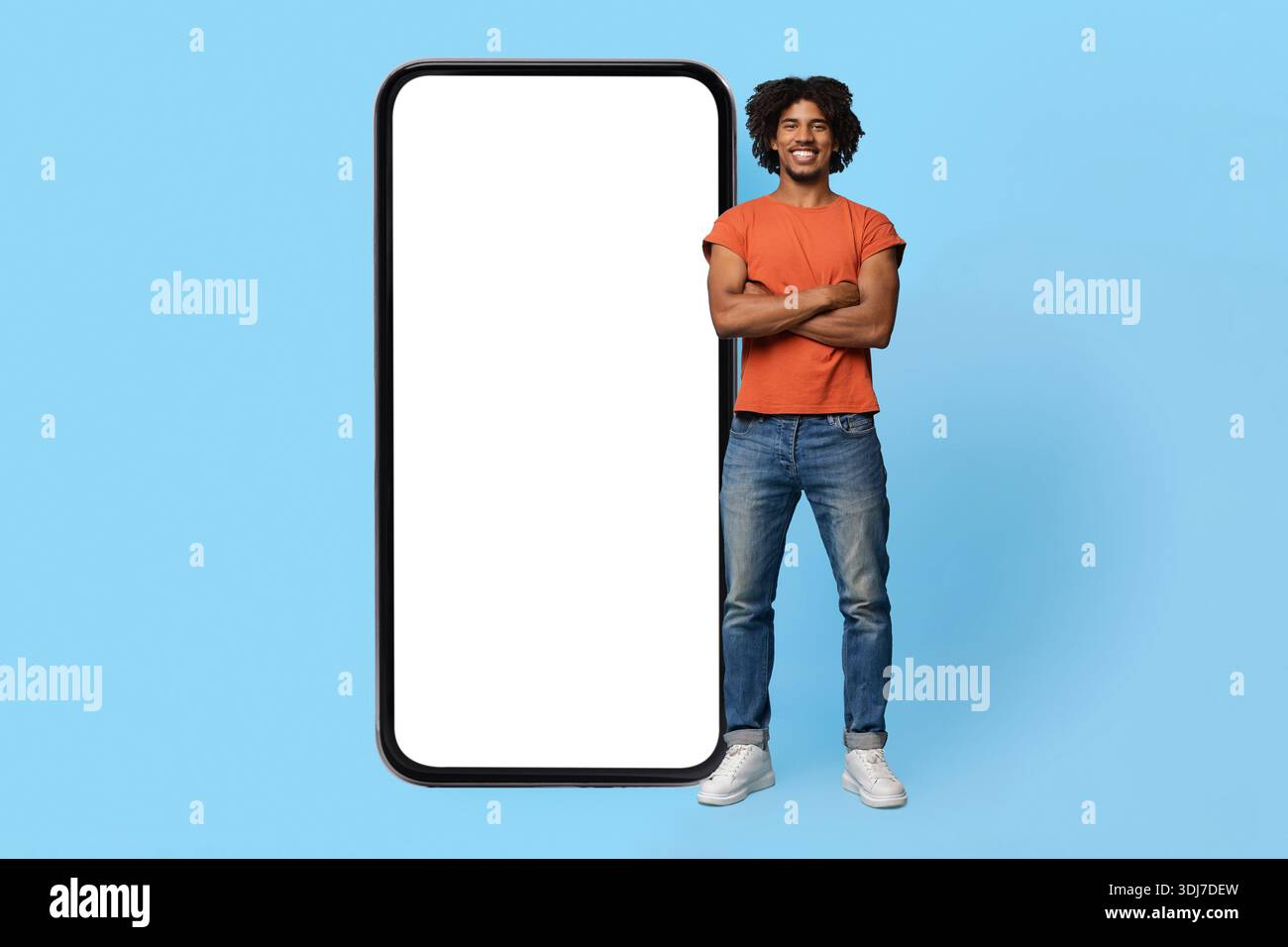 Confident black guy posing by big smartphone with empty screen Stock Photo