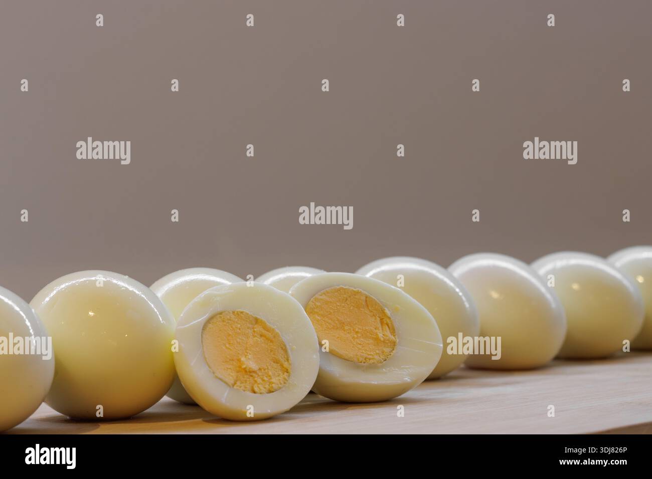 Line of whole and half hard-boiled eggs on a cutting board Stock Photo