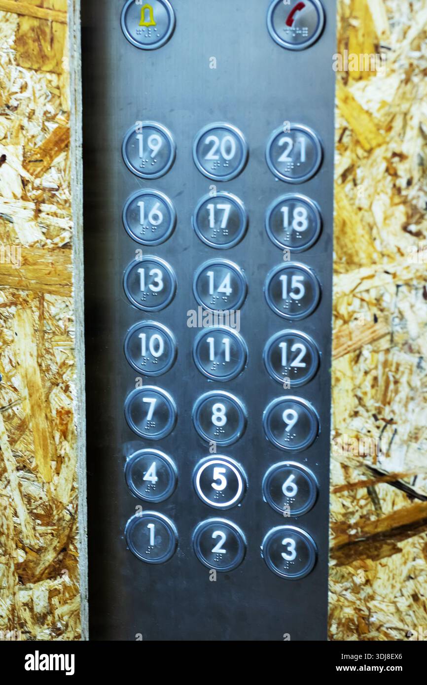 worn metal elevator button panel construction backdrop, closeup vertical view of circular numbered buttons  to , Stock Photo