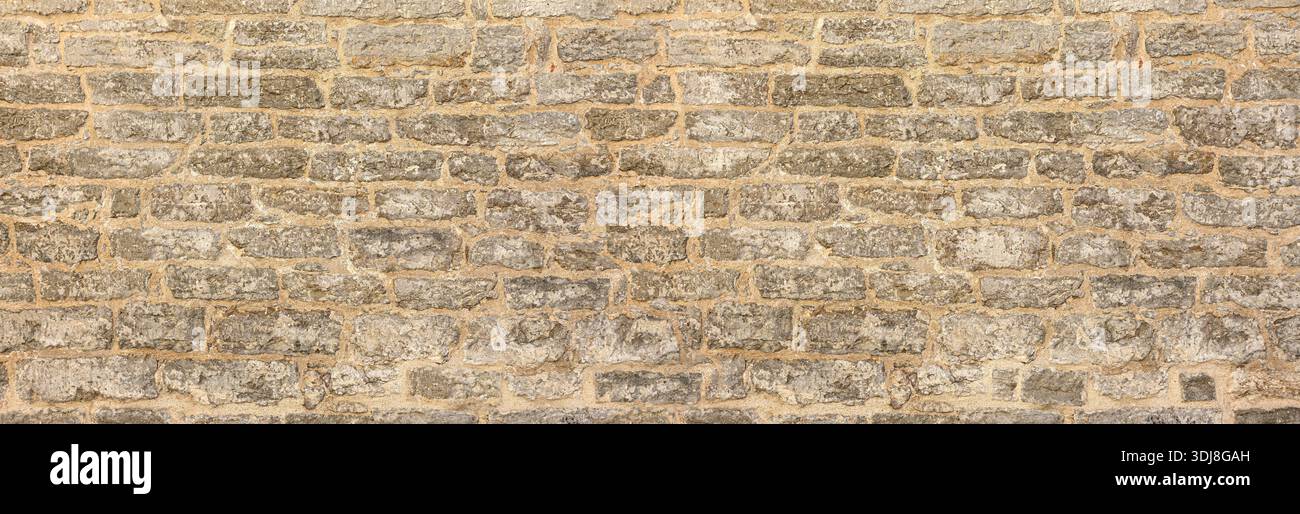 Rough gray stone wall texture forming weathered masonry with mortar joints Stock Photo