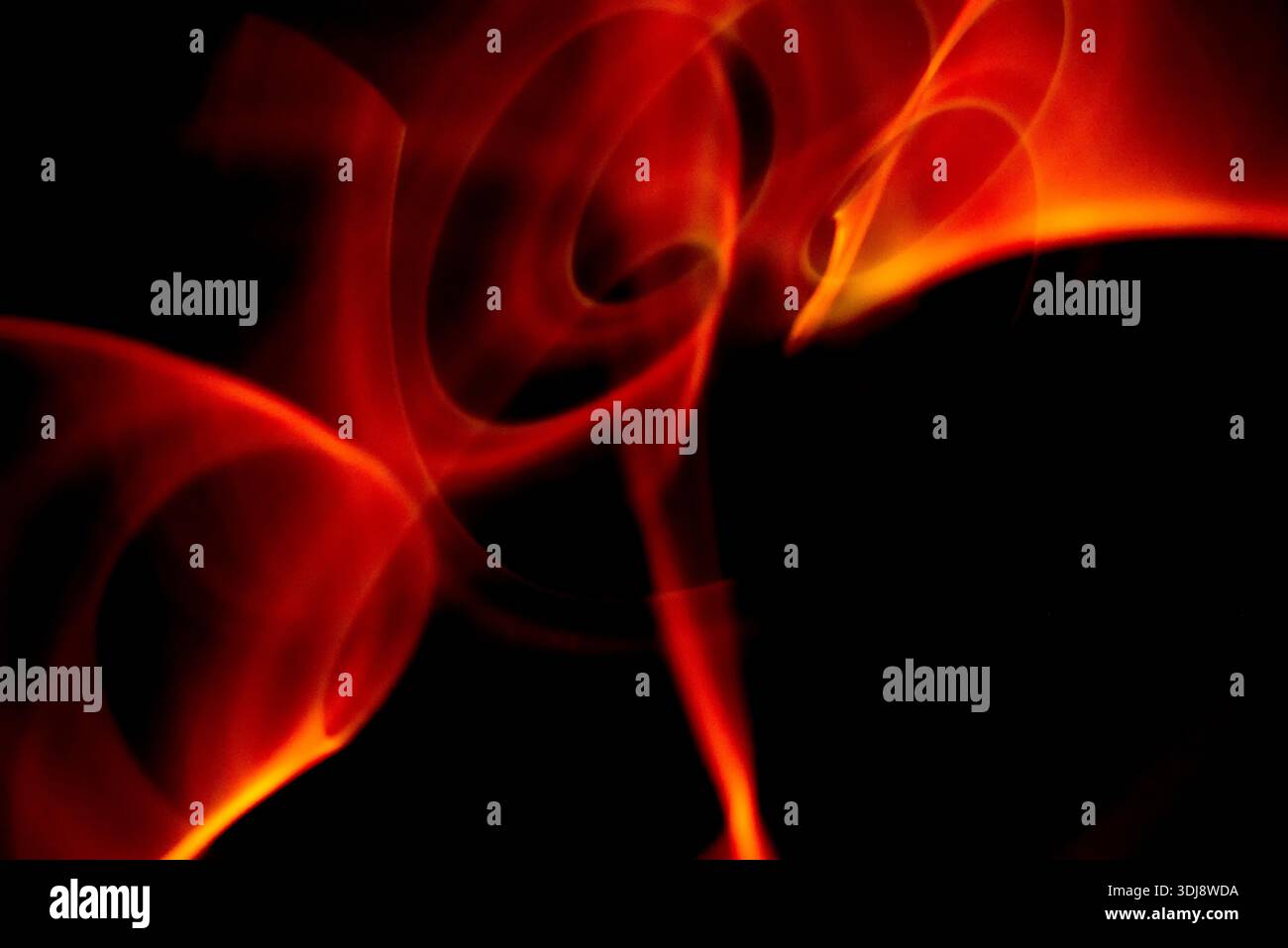 Intense red fire like energy waves forming abstract motion with glowing highlights on dark background. Stock Photo