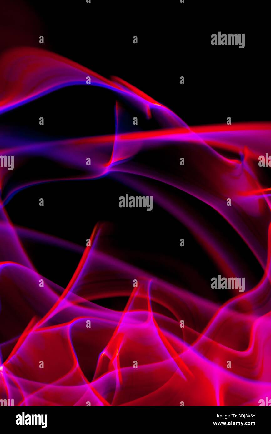 Vertical flowing pink and purple energy lines creating vivid abstract luminous motion. Stock Photo