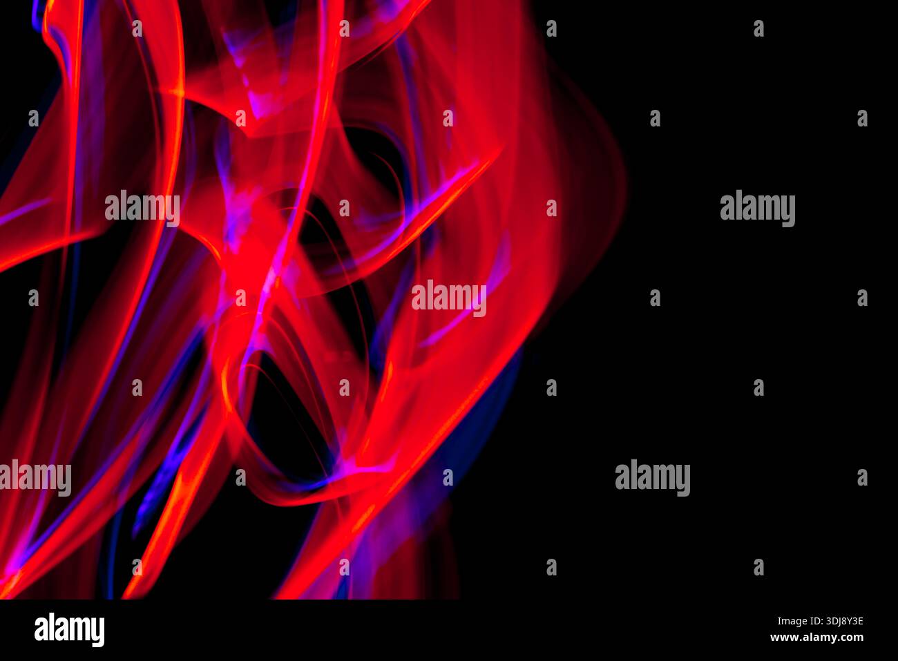 Flowing pink and red luminous lines creating elegant abstract energy movement on dark background. Stock Photo