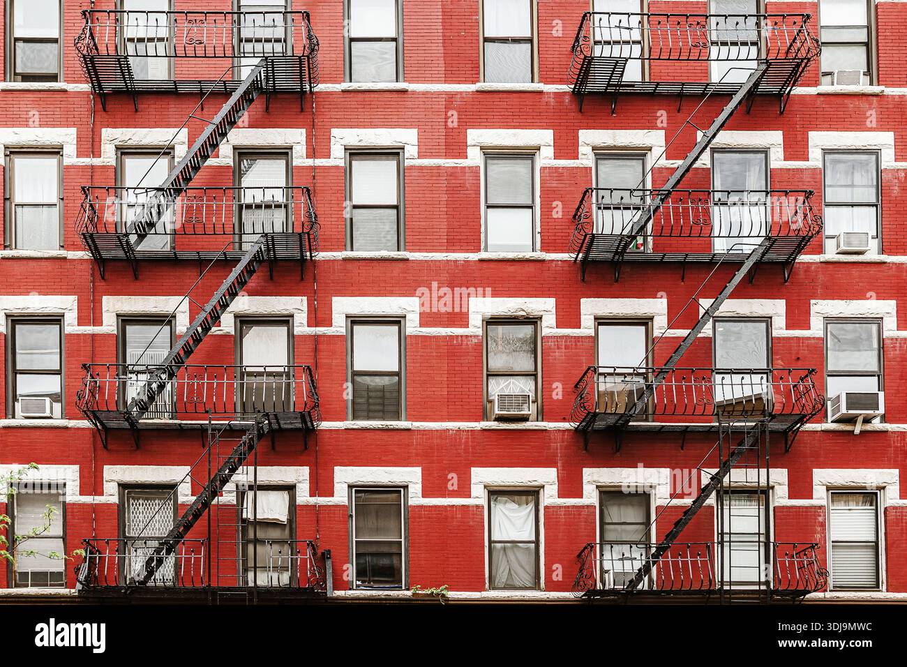 Red brick apartment building facade with classic black fire escapes in ...