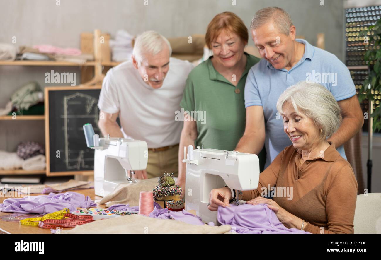 Retired students learning sewing from female instructor in tailoring workshop Stock Photo
