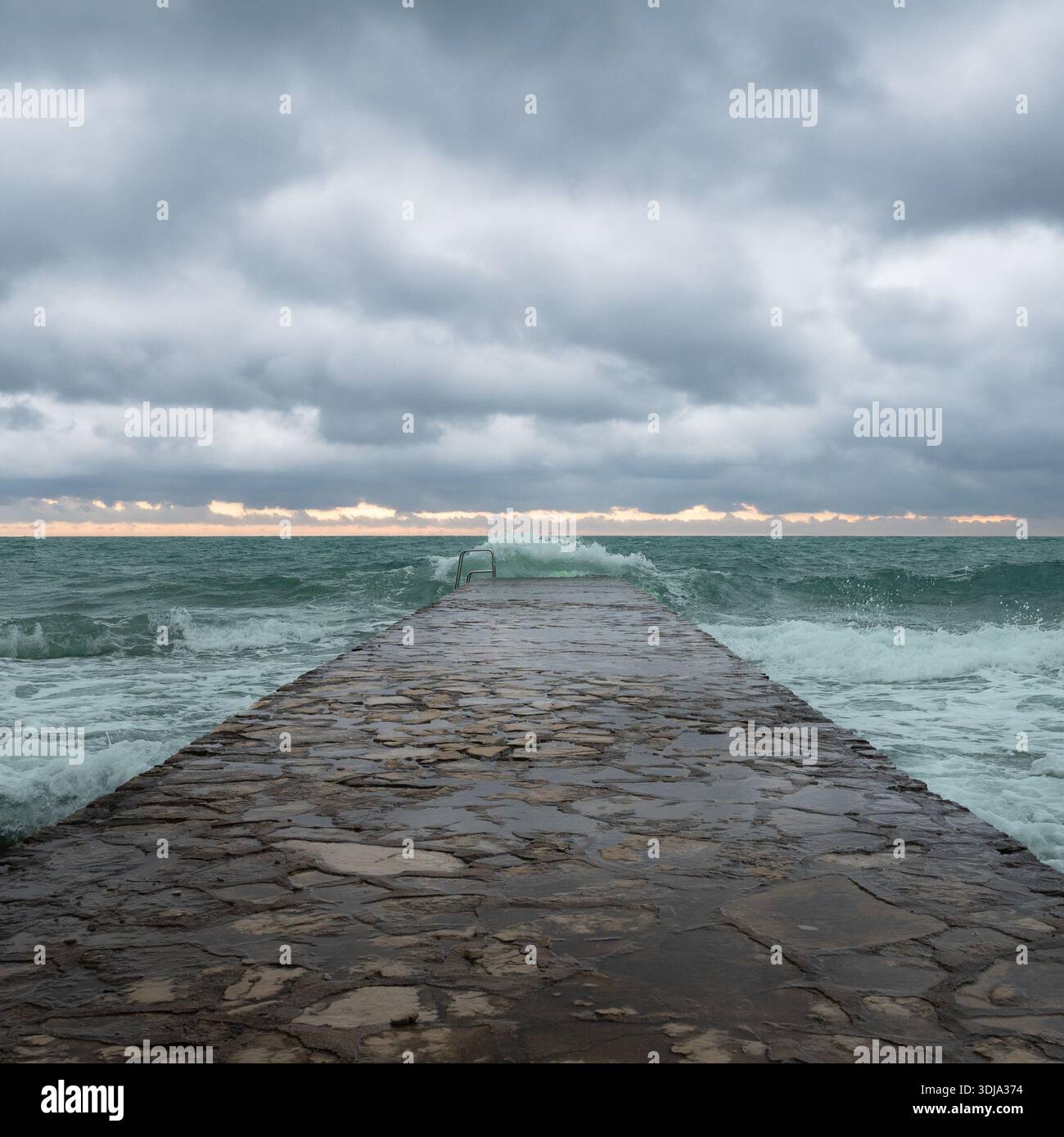 Waves crashing against a stone pier Stock Photo
