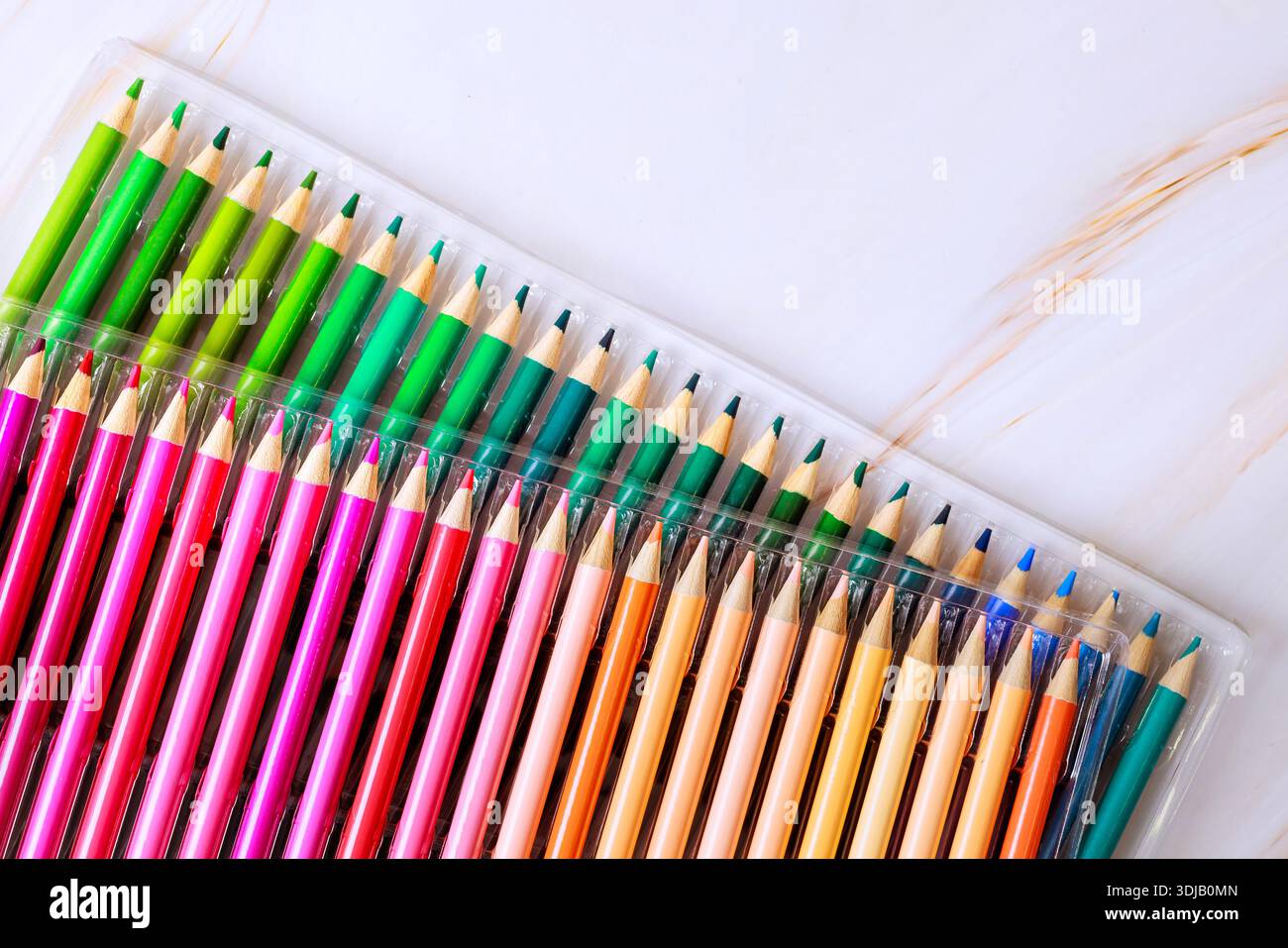 Set of colored pencils with various colors is neatly arranged in plastic case on flat surface. Stock Photo