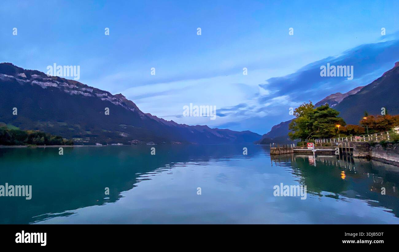 A peaceful twilight view of Lake Brienz (Brienzersee) captured from the shores of Bönigen, Switzerland. The image features the silhouette of the Swiss - Smartphone Captured Stock Image