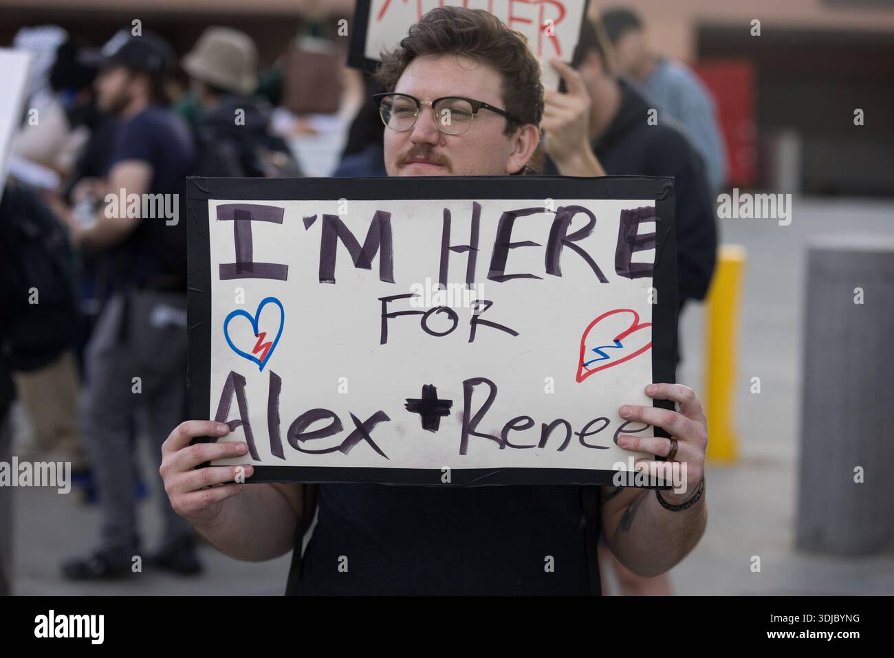 A demonstrator holds a sign reading “I’m here for Alex + Rene” outside ...