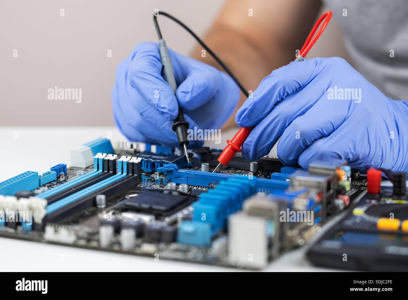 Technician under fixed and repairing computer mainboard process by used multimeter AC Voltage for analysis on computer mainboard is electronic compone Stock Photo