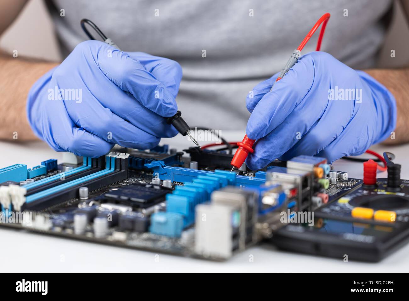Technician under fixed and repairing computer mainboard process by used multimeter AC Voltage for analysis on computer mainboard is electronic compone Stock Photo