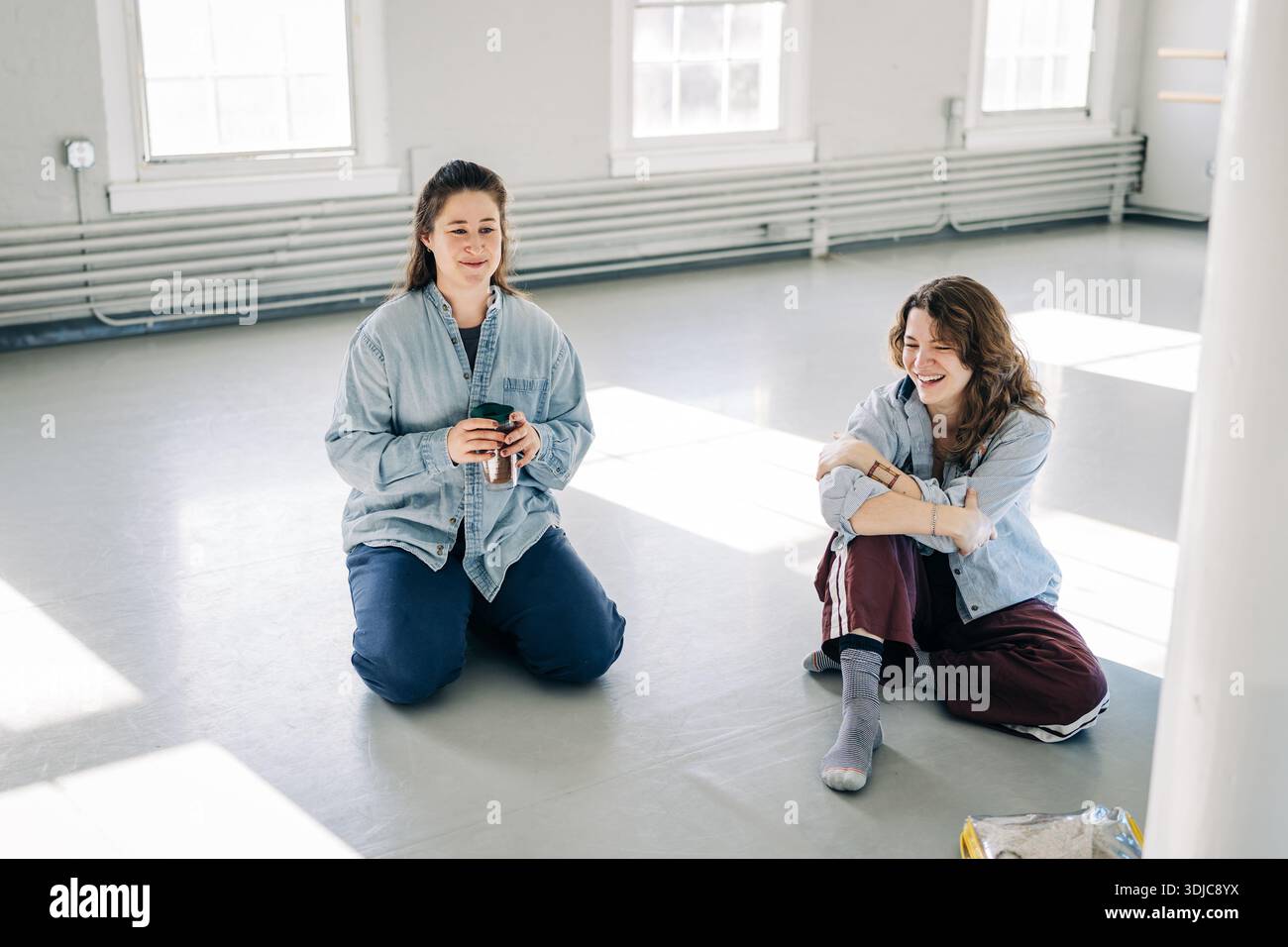 Two young women talking and laughing in studio Stock Photo