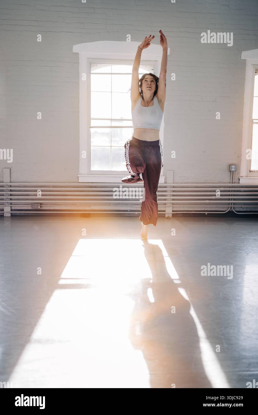 Female dancer balancing in bright sunlit studio Stock Photo