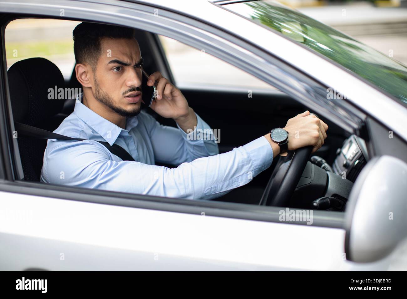 Angry arabic guy manager fighting on phone while driving auto Stock Photo
