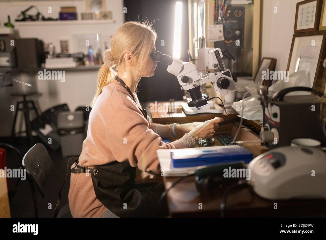 Woman examining intricate details using microscope in workshop Stock Photo
