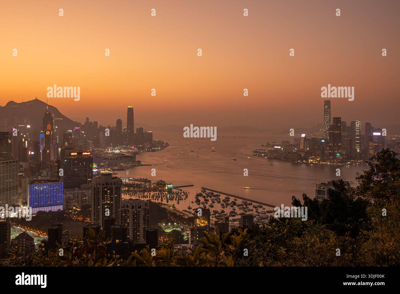 Elevated panoramic view of the Hong Kong skyline and Victoria Harbour at sunset. Stock Photo