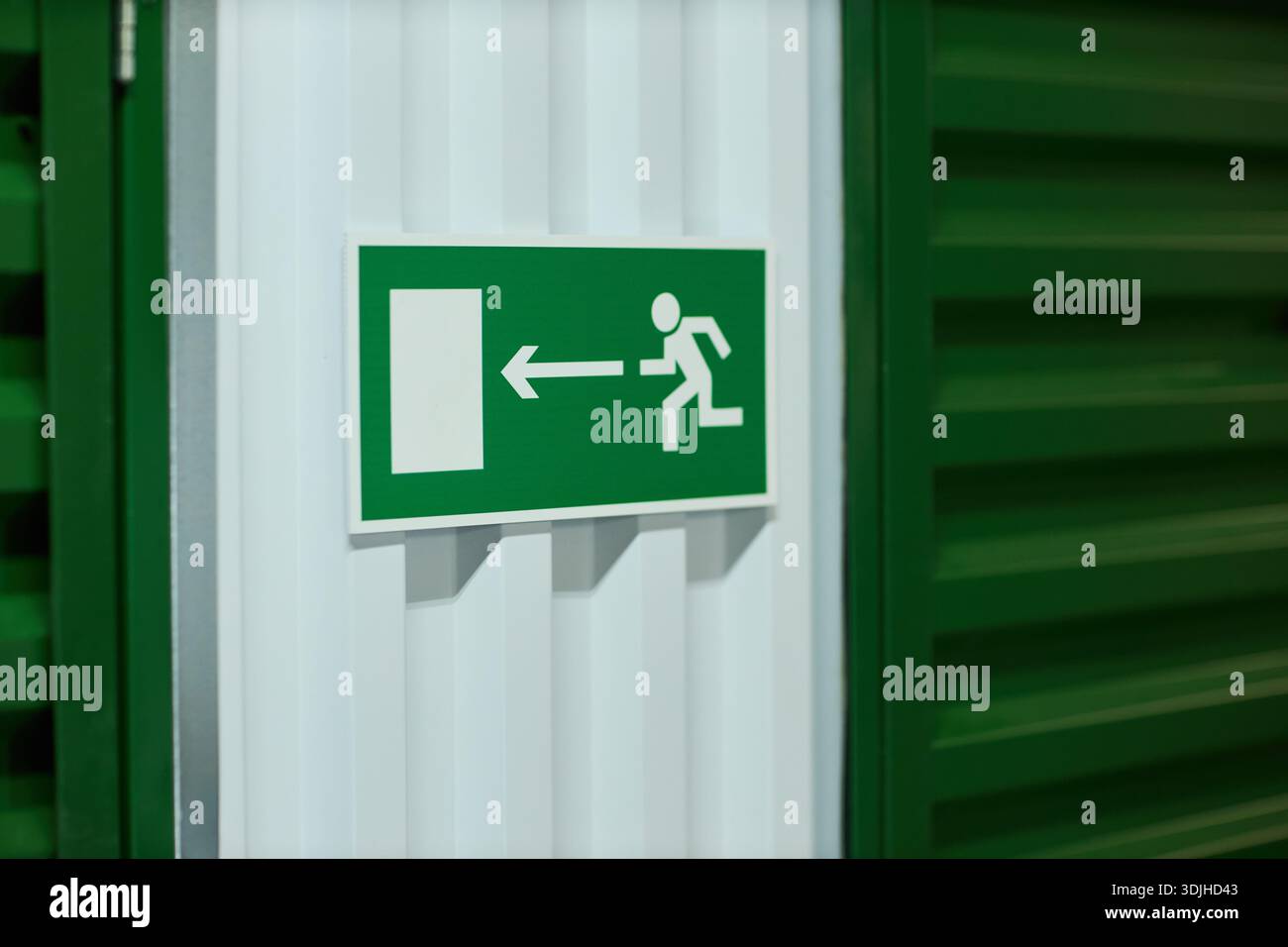 Emergency exit sign showing running figure and arrow pointing left ...