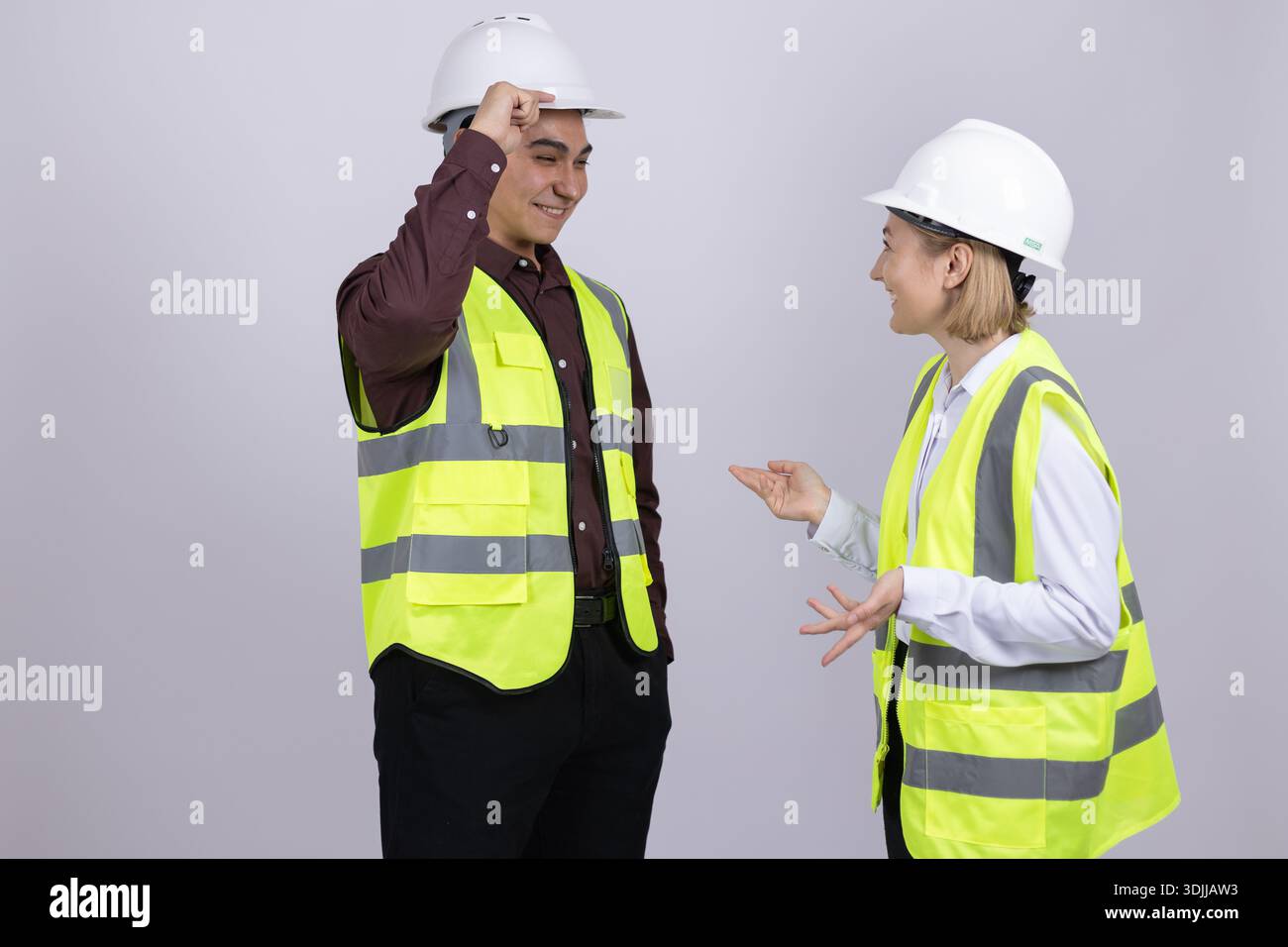 Two construction workers in safety vests talking together Stock Photo