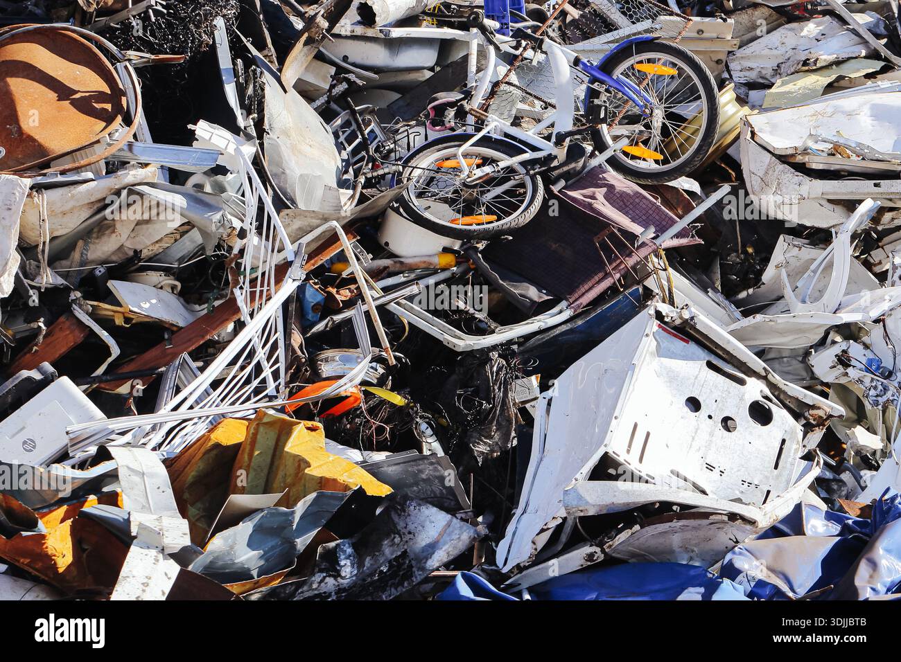 Scrap metal and electronic waste pile at recycling yard. Discarded appliances bicycles and parts. Environmental pollution and recycling industry. Stock Photo