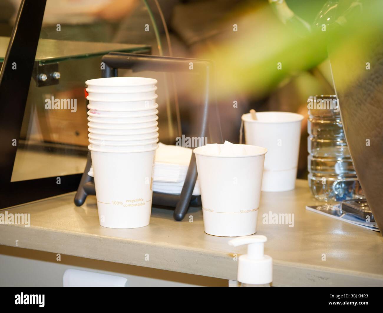 Stack of disposable paper coffee cups on a café counter, takeaway hot drink service concept in a modern coffee shop interior. Stock Photo