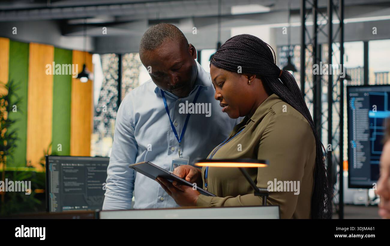 Team of software developers in office automating workflows using artificial intelligence. IT staff members refining deep learning computational models for faster processing, camera B Stock Photo