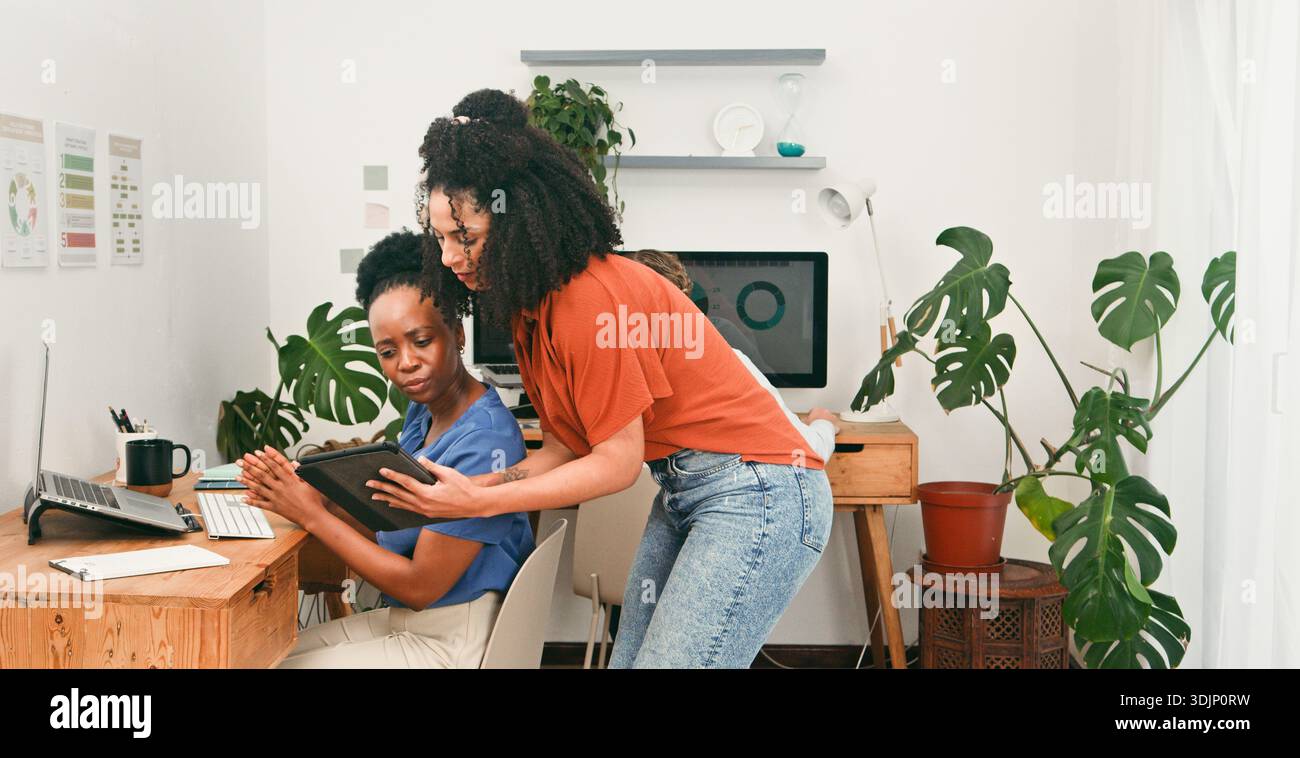 Collaborative Office Scene With Two Women Working On Tablet And Computer Stock Photo