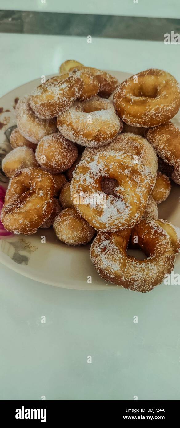 Golden brown homemade donuts coated in granulated sugar, served on floral-patterned plate with inviting presentation. - Smartphone Captured Stock Image