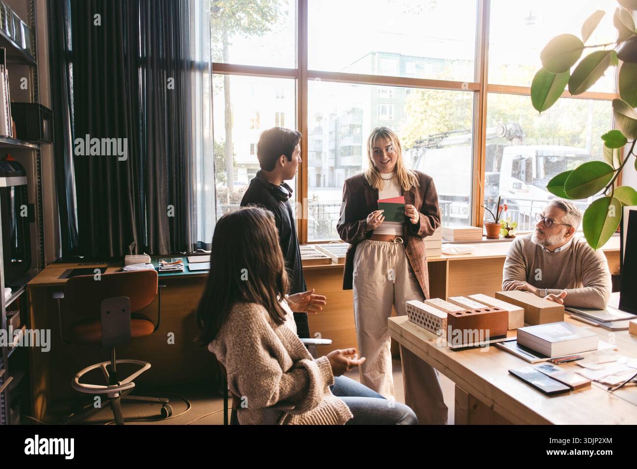Female creative professional sharing design plan with team in office Stock Photo