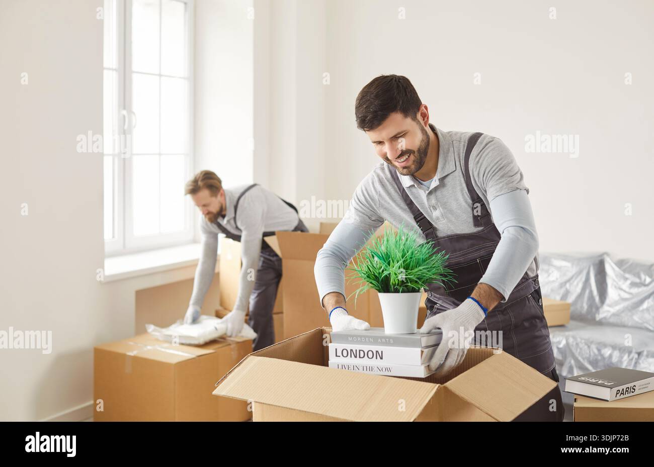 Smiling movers packing household items into boxes during efficient relocation Stock Photo