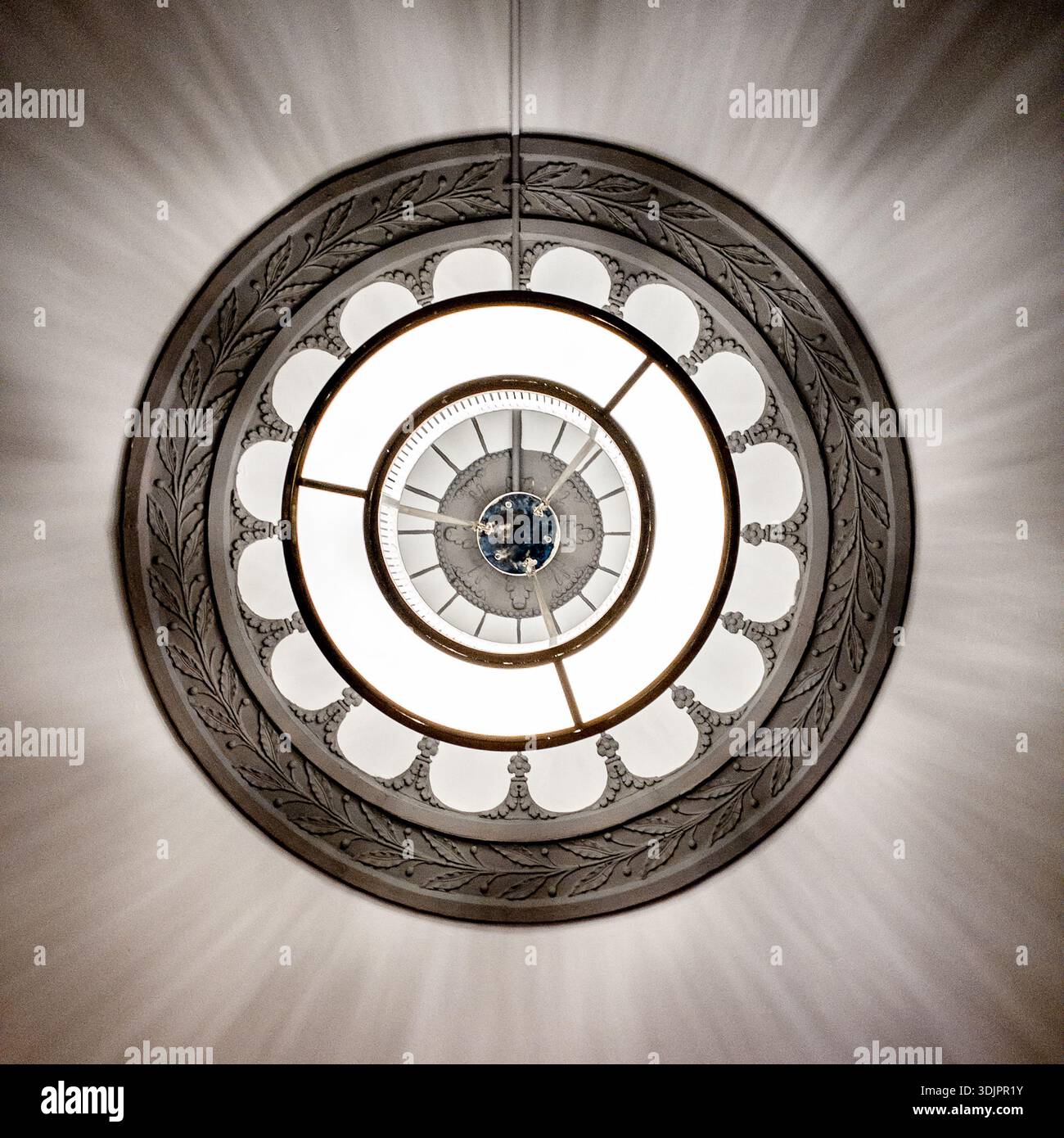 Ornate circular ceiling  chandelier in a Victorian-era building interior, with glowing light creating a dramatic lens flare effect - Smartphone Captured Stock Image
