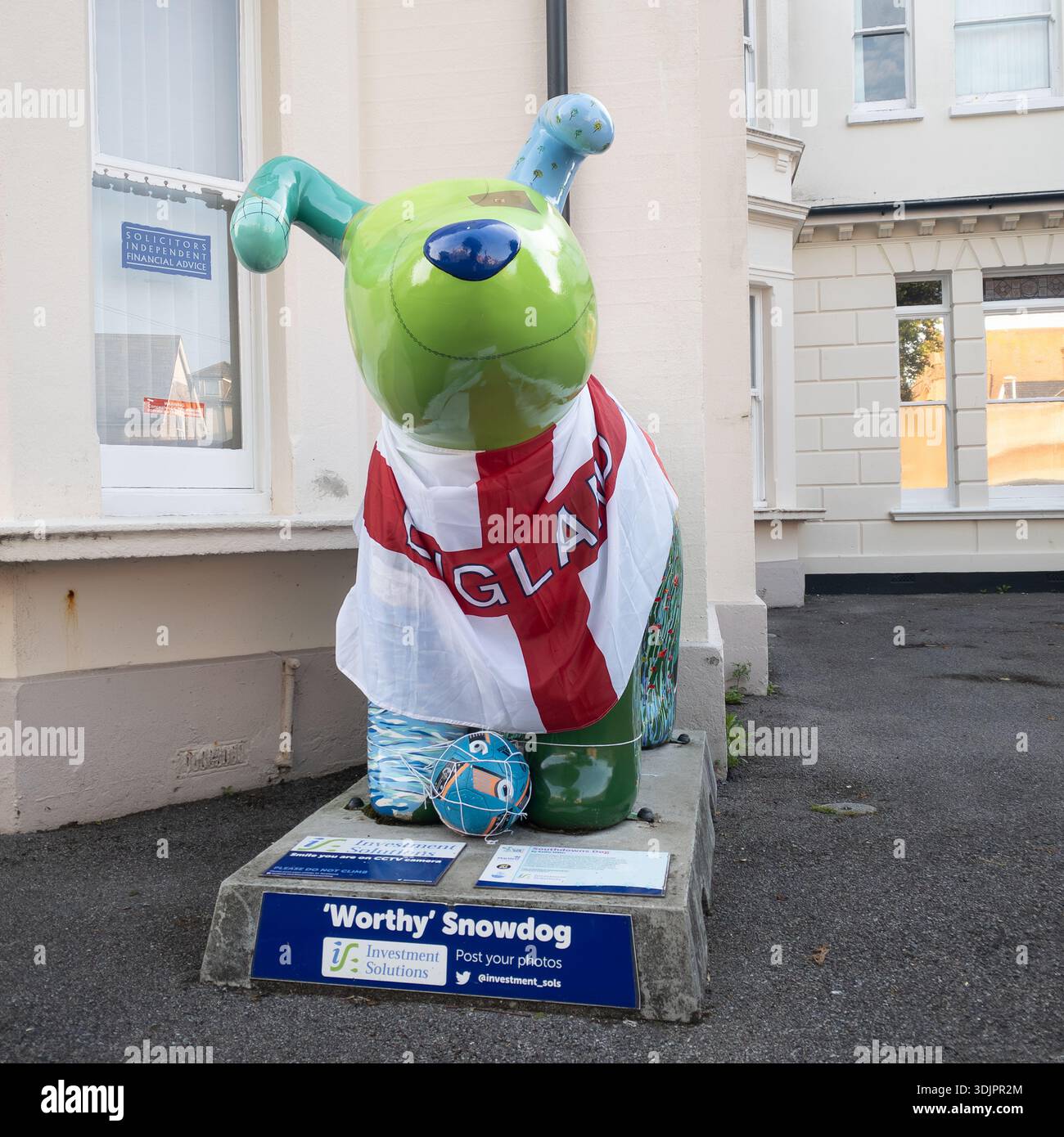 Worthy Snowdog sculpture painted green with England football flag draped over it and a football at its paws, part of the public art trail outside a Wo - Smartphone Captured Stock Image