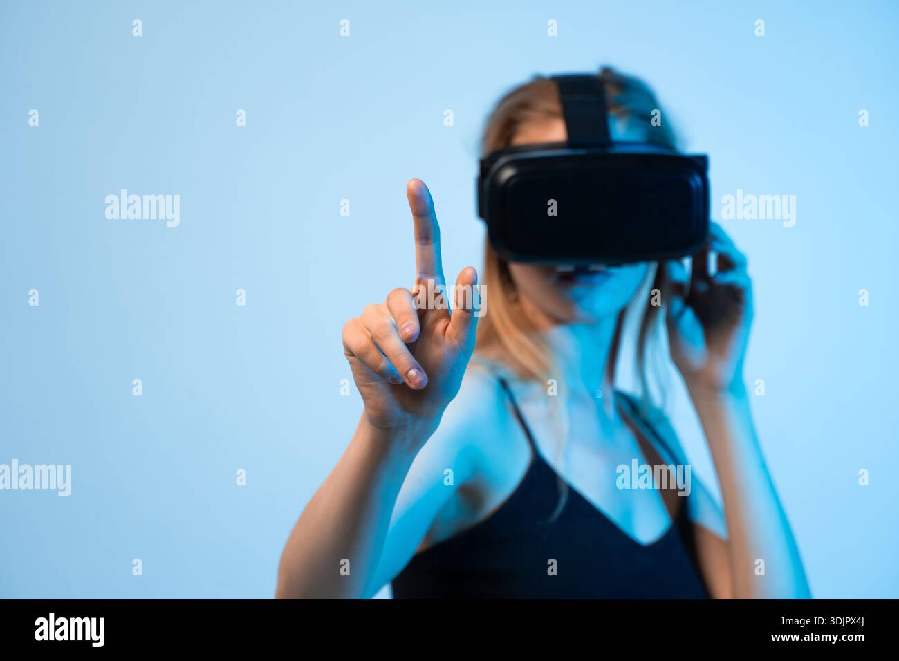 Female user interacting with virtual interface using VR headset, finger pointing gesture and immersive technology concept Stock Photo