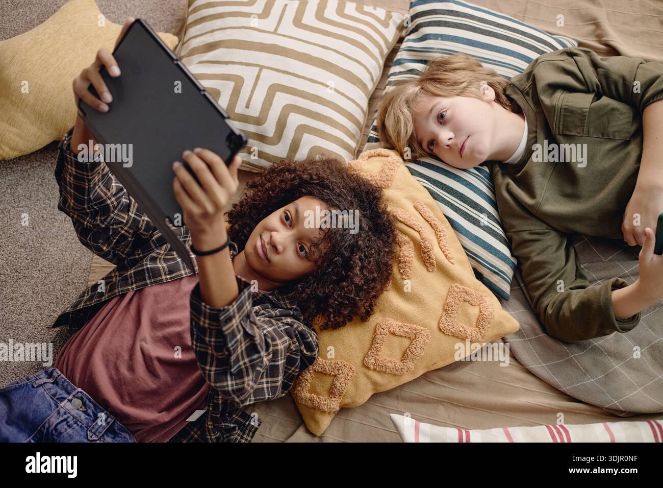 Multiethnic Generation Alpha Children Lying on Floor Using Digital Tablet Together Stock Photo