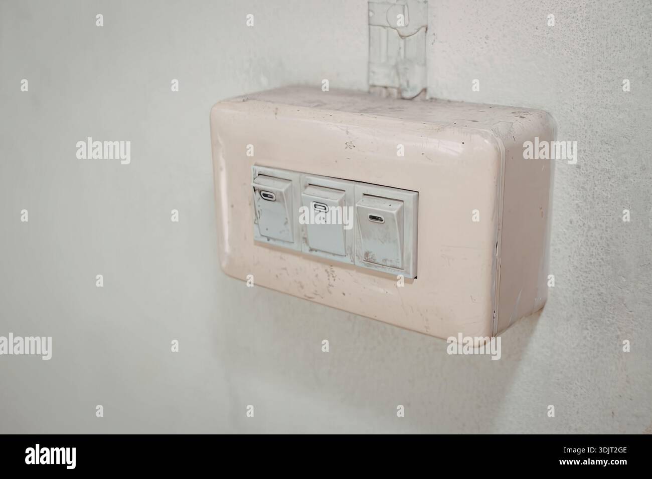 A beige-colored wall-mounted electrical outlet box with three sockets ...