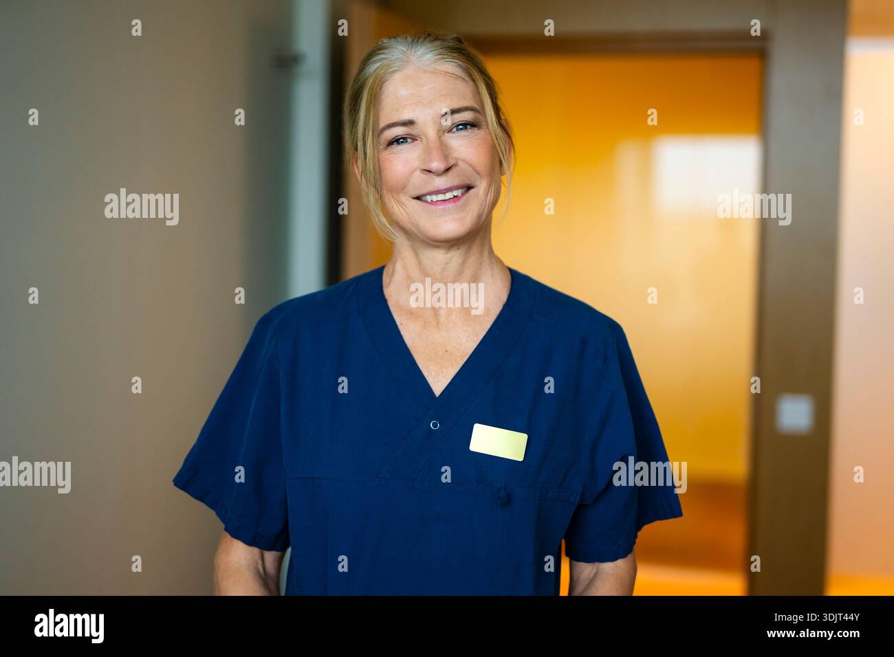 Portrait of smiling senior female doctor wearing scrubs Stock Photo