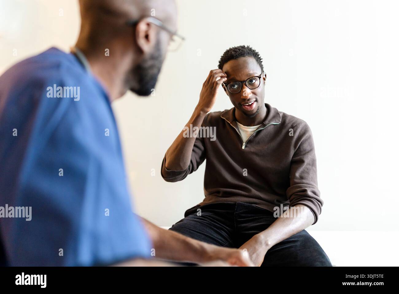 Young man with hearing disability communicating through sign language during doctor's visit Stock Photo