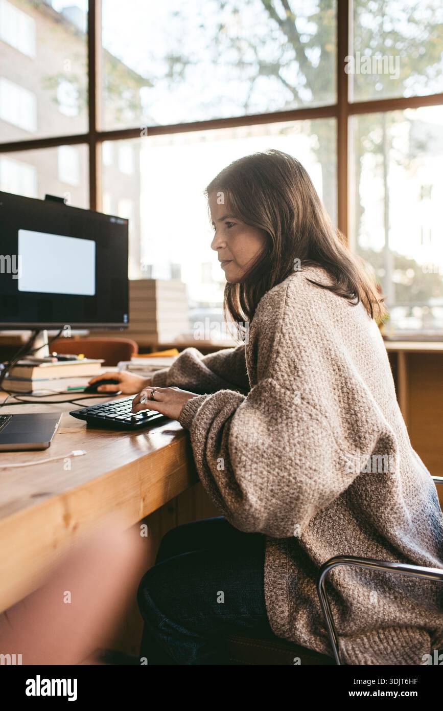 Focused mature female creative business expert working on technologies in office Stock Photo