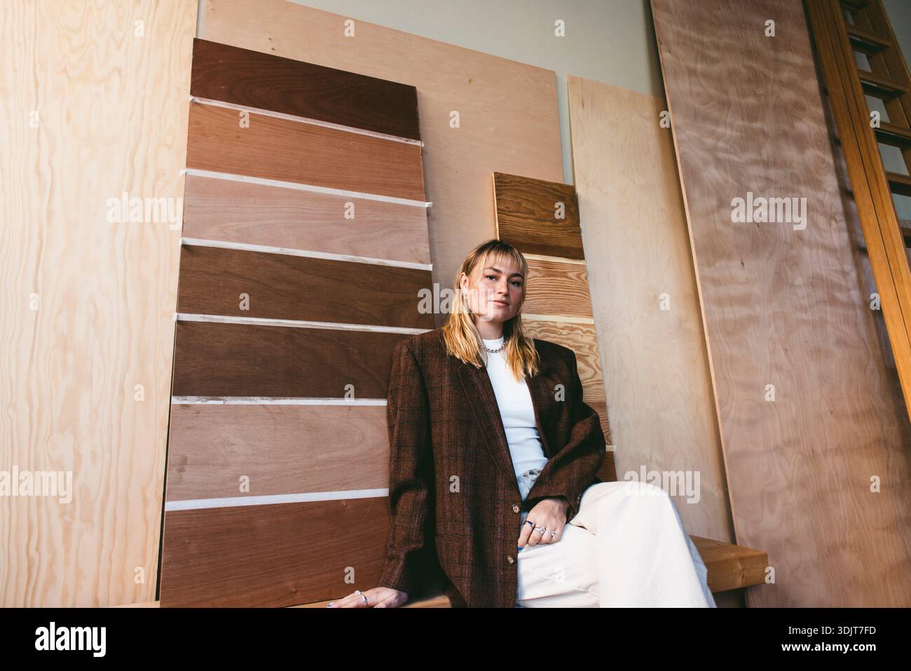 Portrait of confident female design professional sitting against different wood samples mounted on wall in office Stock Photo
