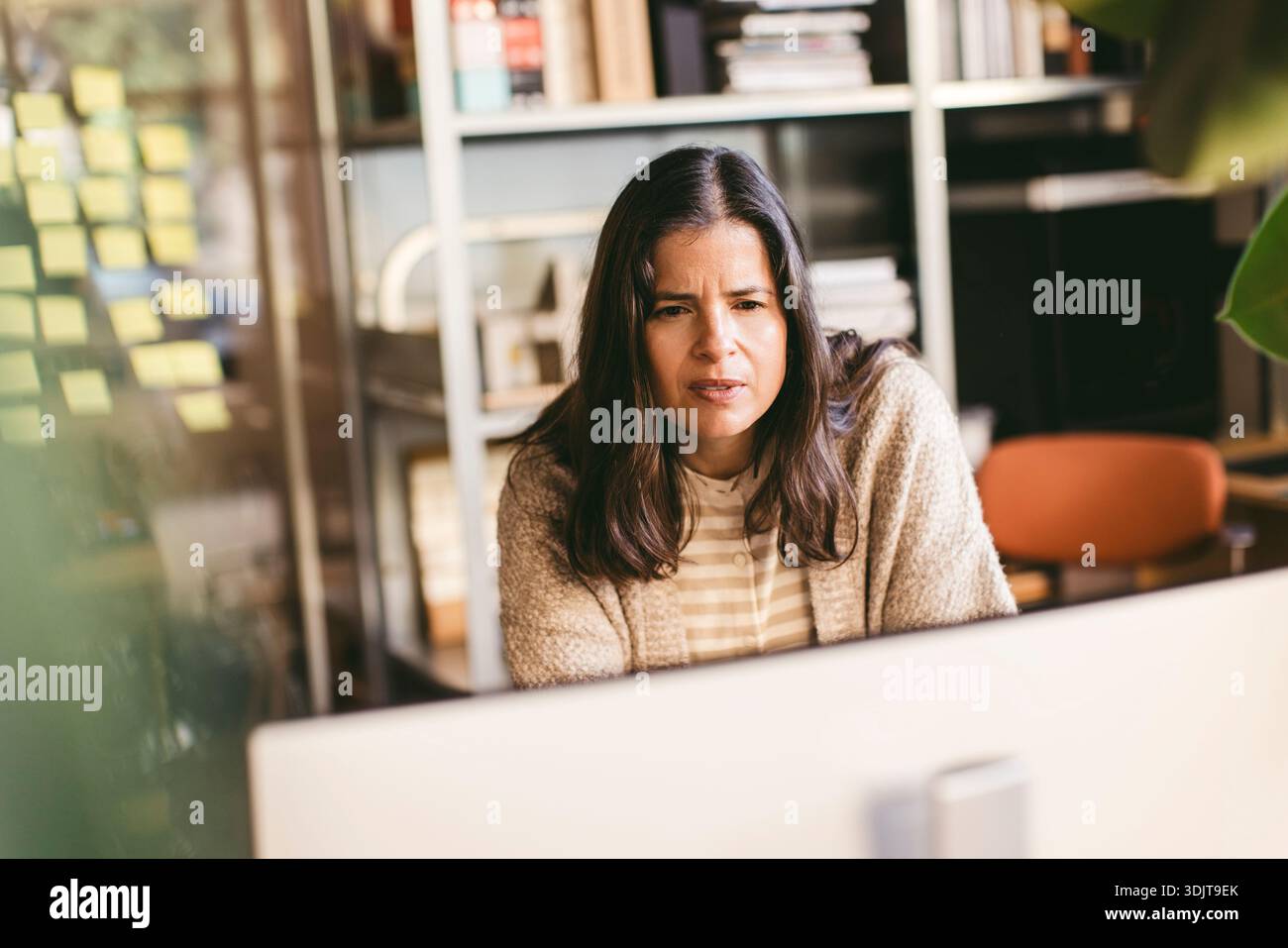 Thoughtful mature female design expert working on computer in office Stock Photo