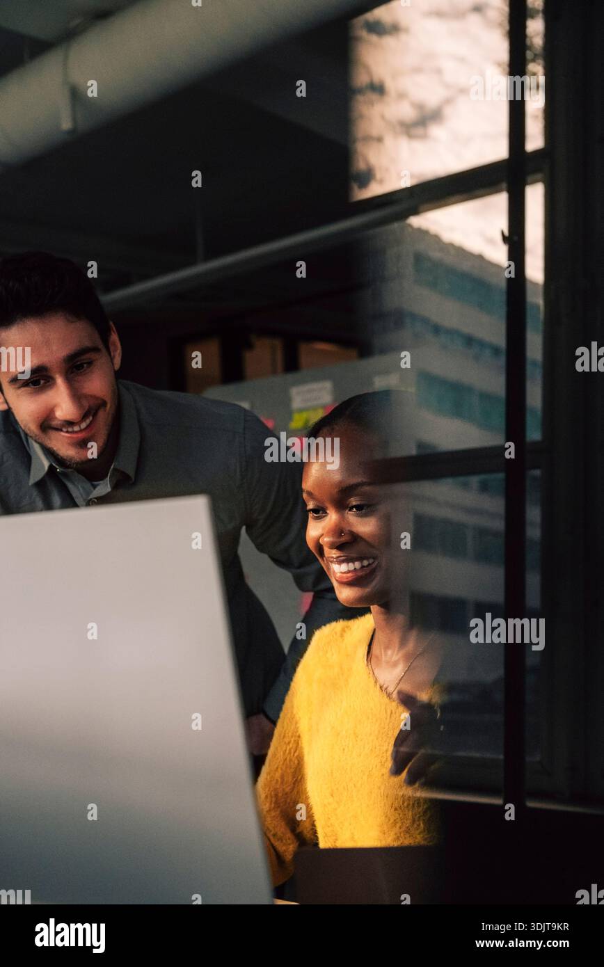 Smiling female programmer using computer while working with male colleague in tech office Stock Photo
