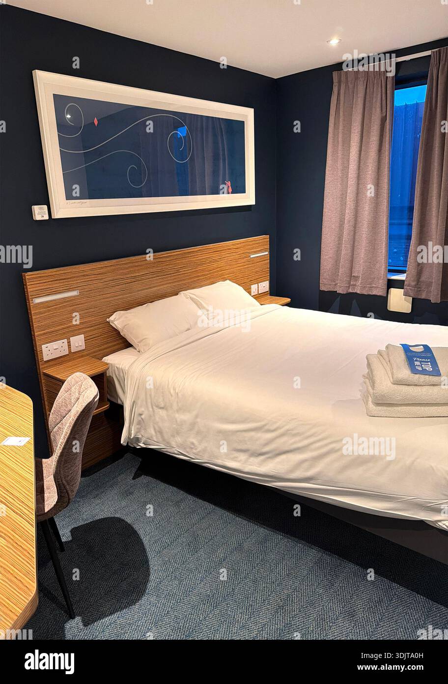 Modern Travelodge hotel room featuring a comfortable bed, stylish decor, and inviting ambiance for relaxation and rest - Smartphone Captured Stock Image