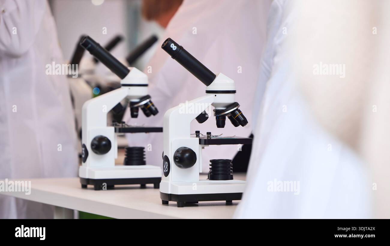 Students in lab coats using microscopes for science education Stock Photo