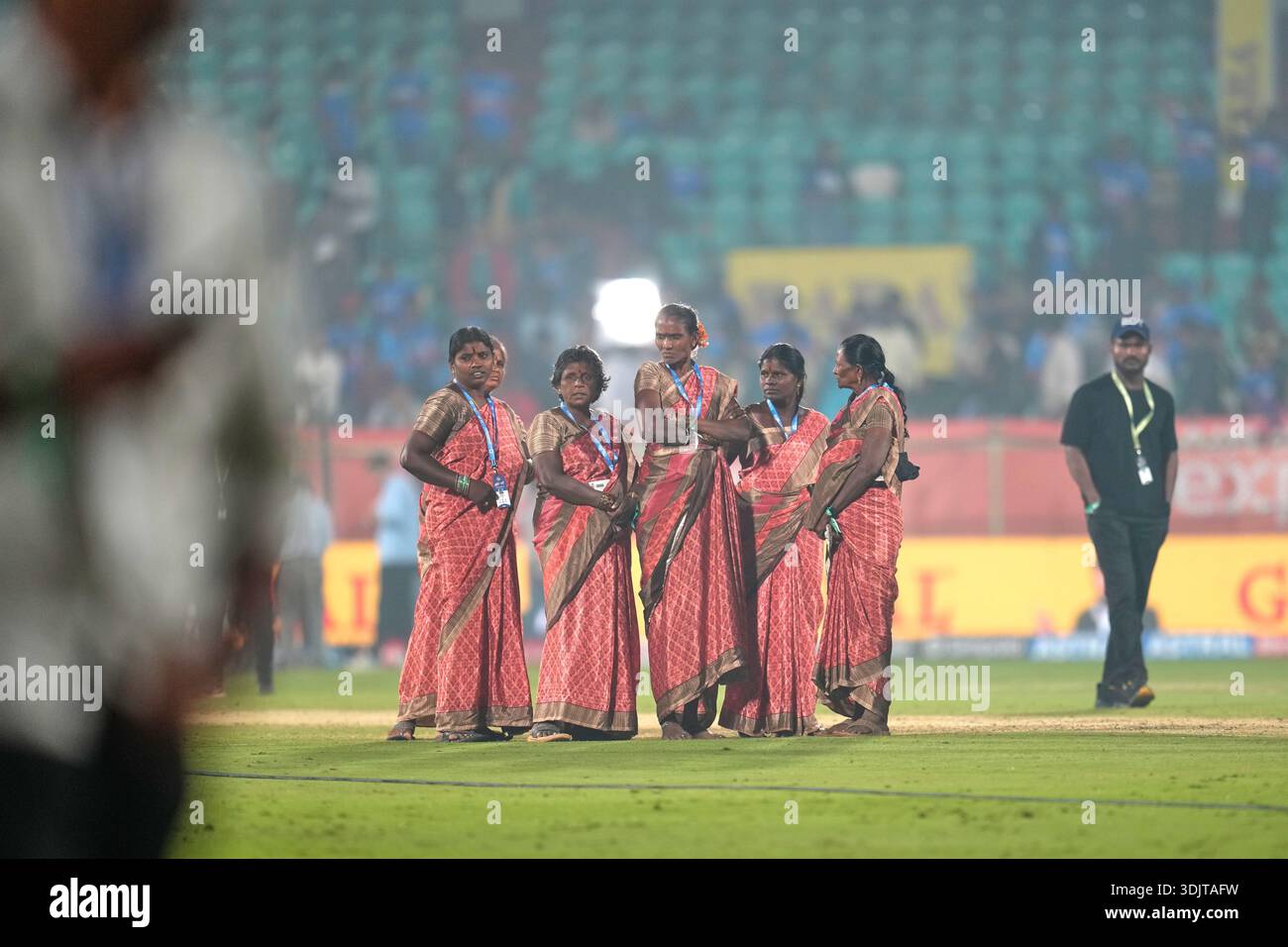 Ground women staff standing near the pitch watch as New Zealand and ...