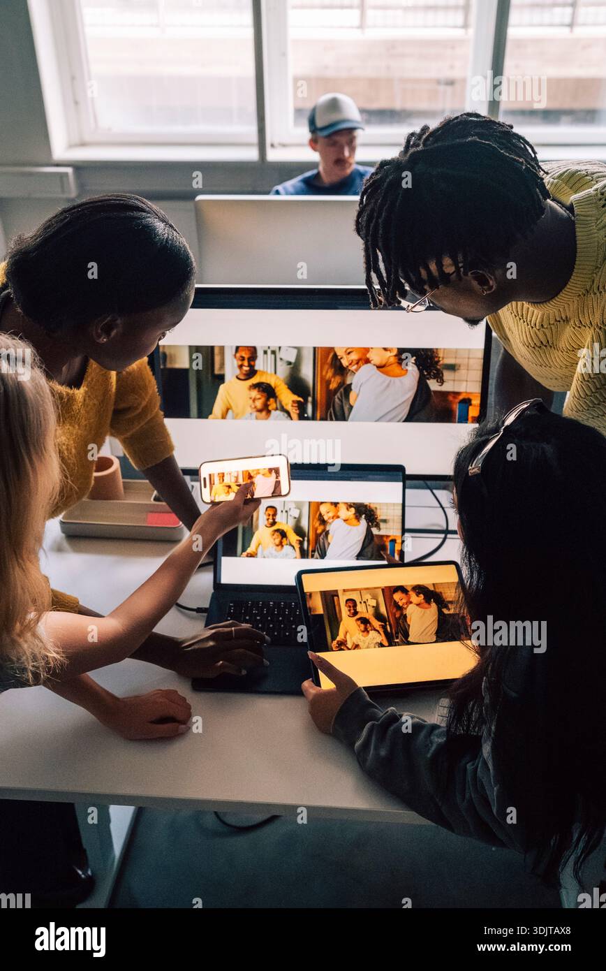 High angle view of creative professionals comparing software design preview on different technologies while working in t Stock Photo
